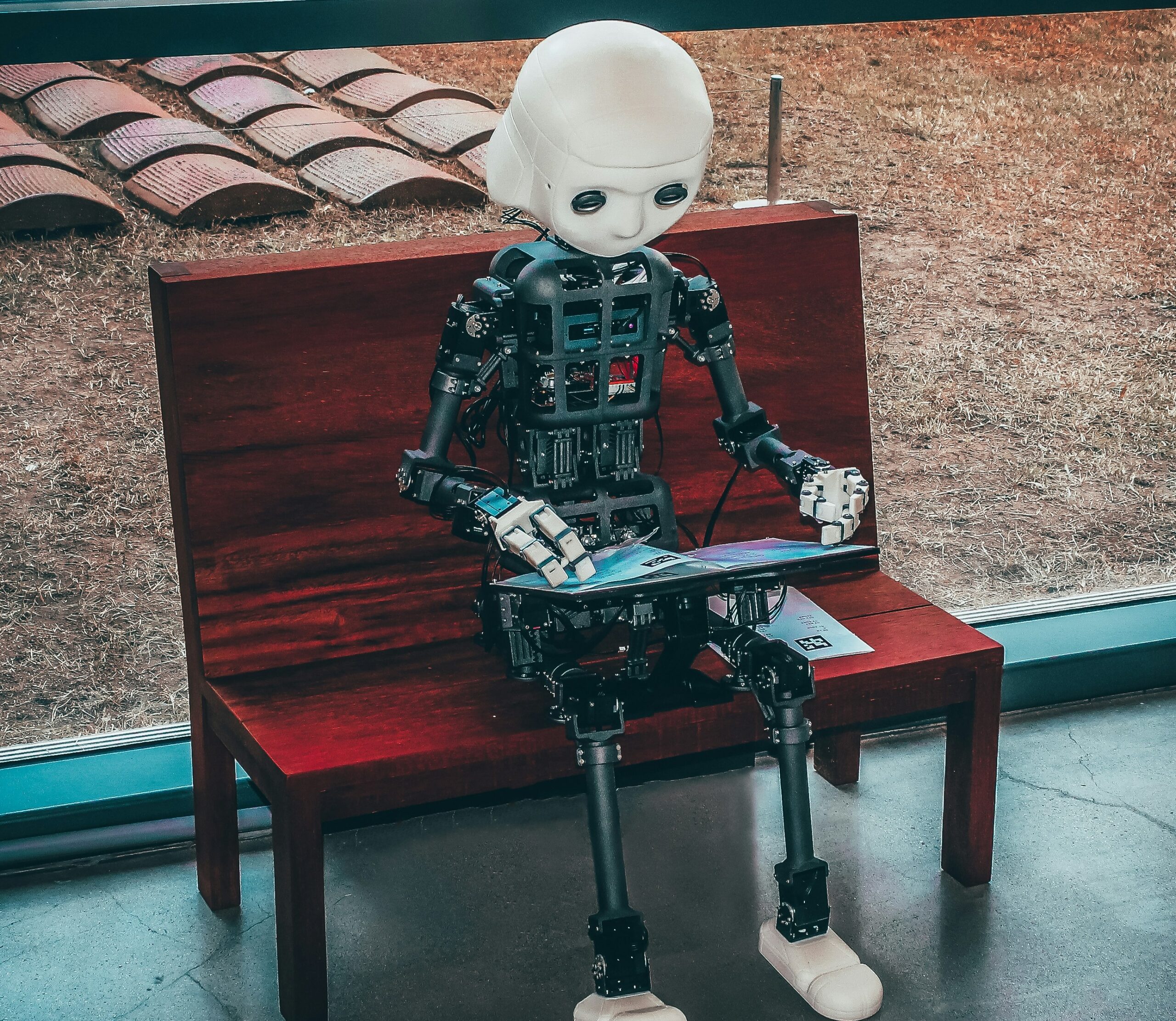 picture of a AI type robot on a bench with reading material.